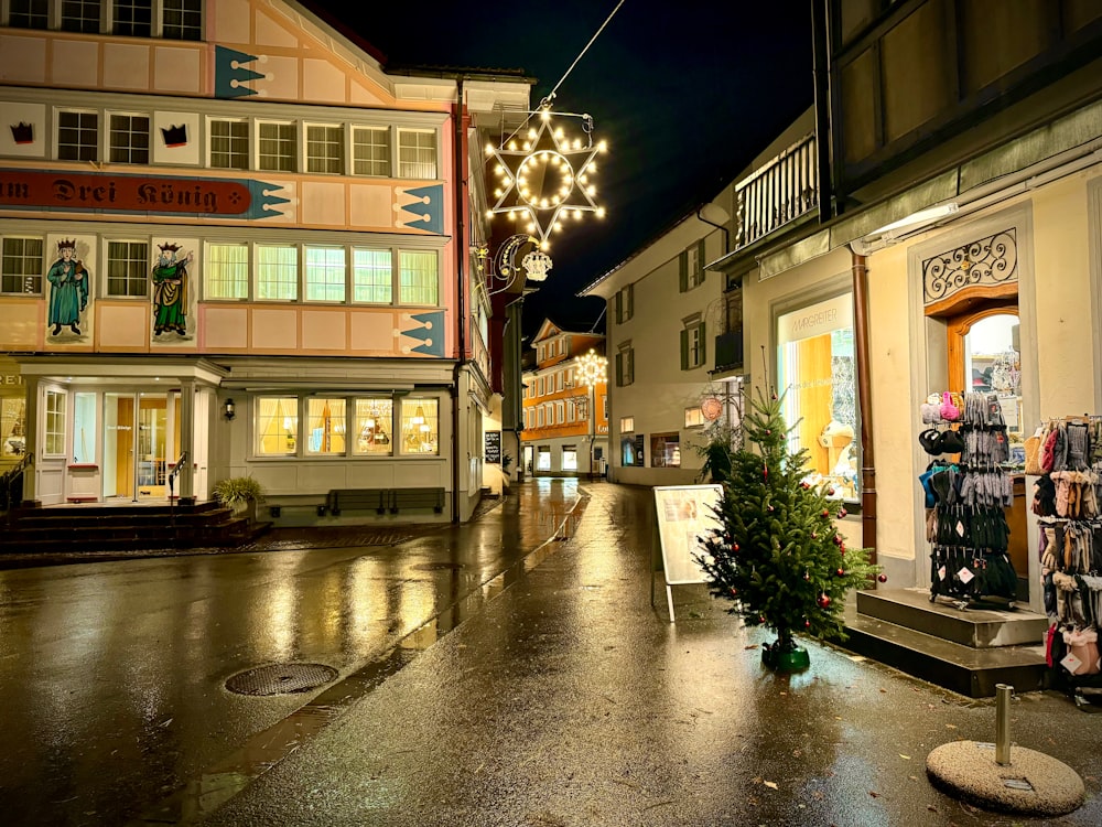 a city street at night with a christmas tree in the middle of the street