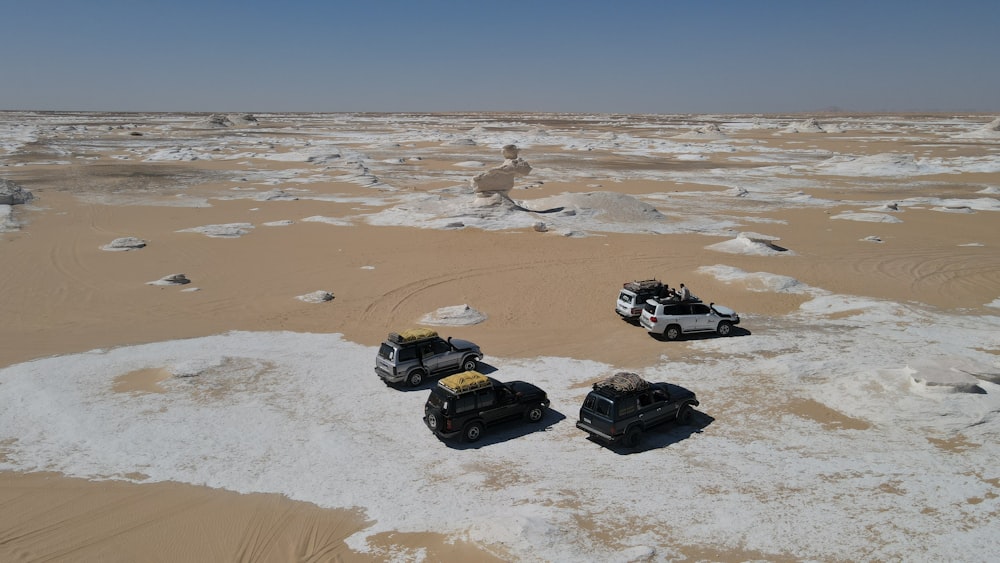 a group of four vehicles driving across a desert