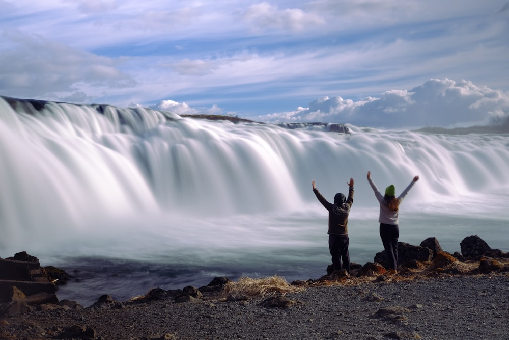 a couple of people standing in front of a waterfall