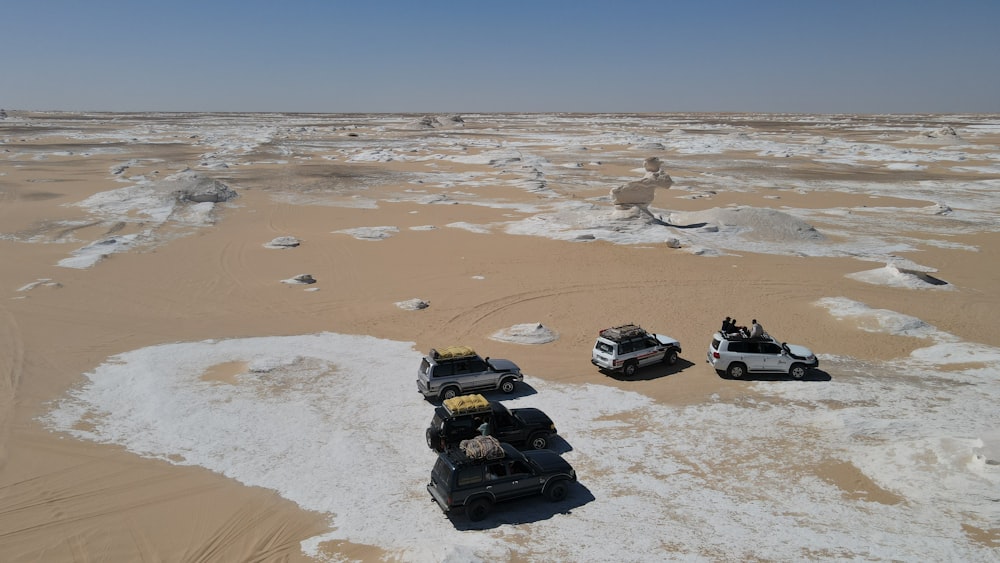 a group of four vehicles driving through a desert