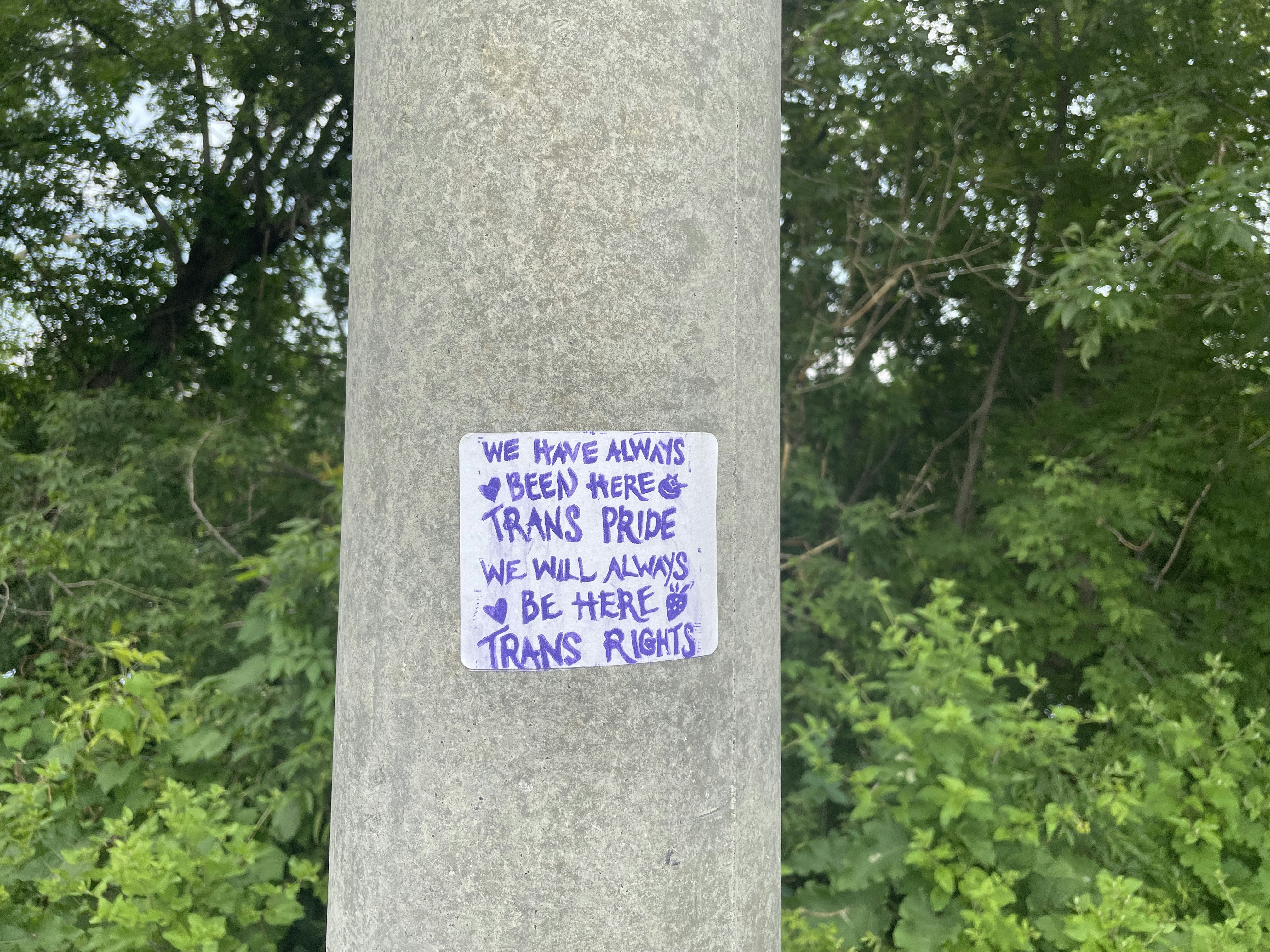 a sticker on a pole in front of some trees