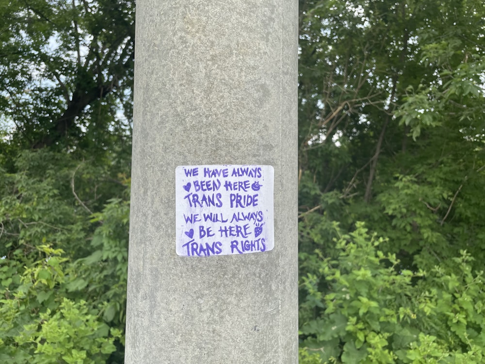 a sticker on a pole in front of some trees