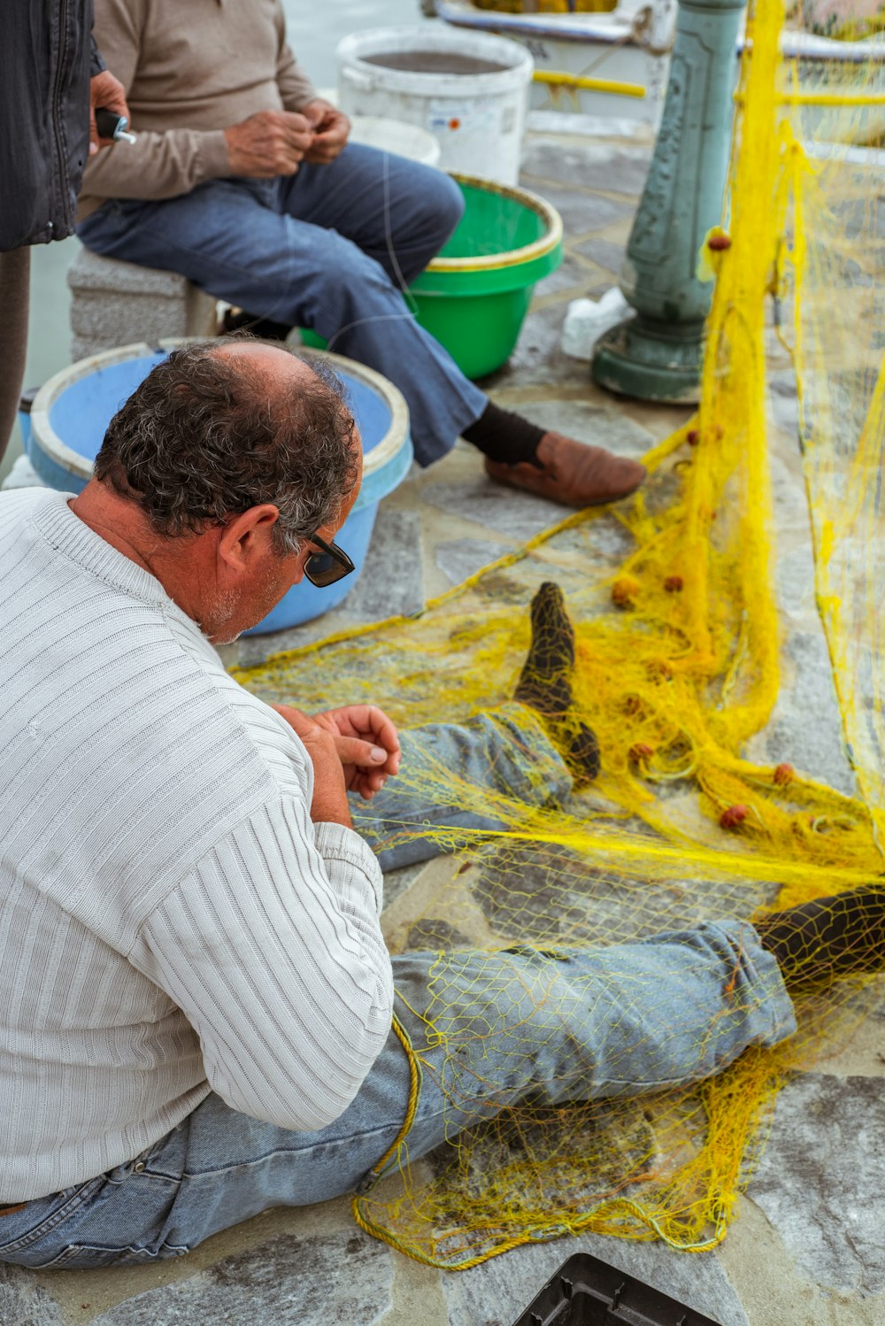 a man sitting on the ground next to a yellow net