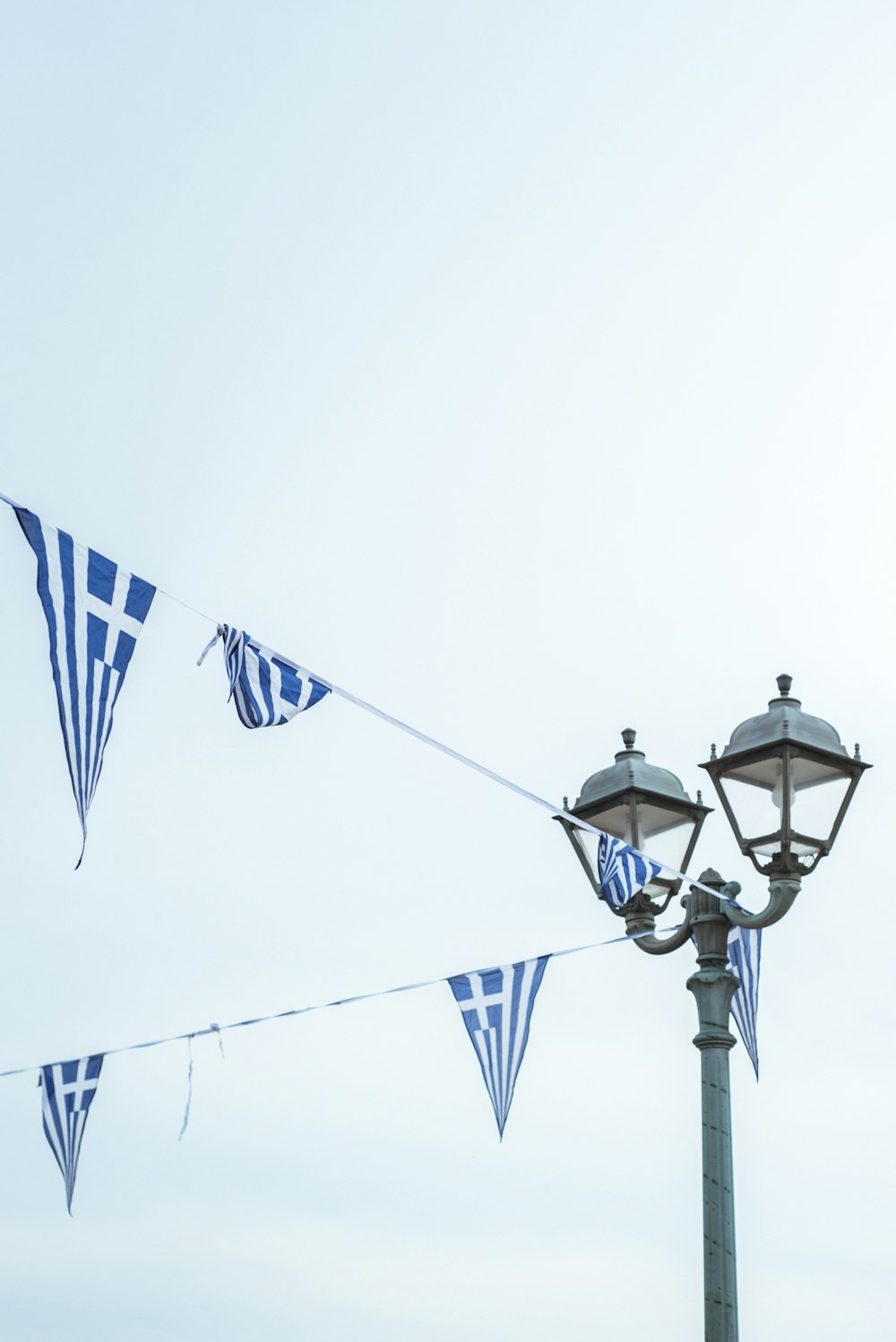 blue and white flags hanging from a street light