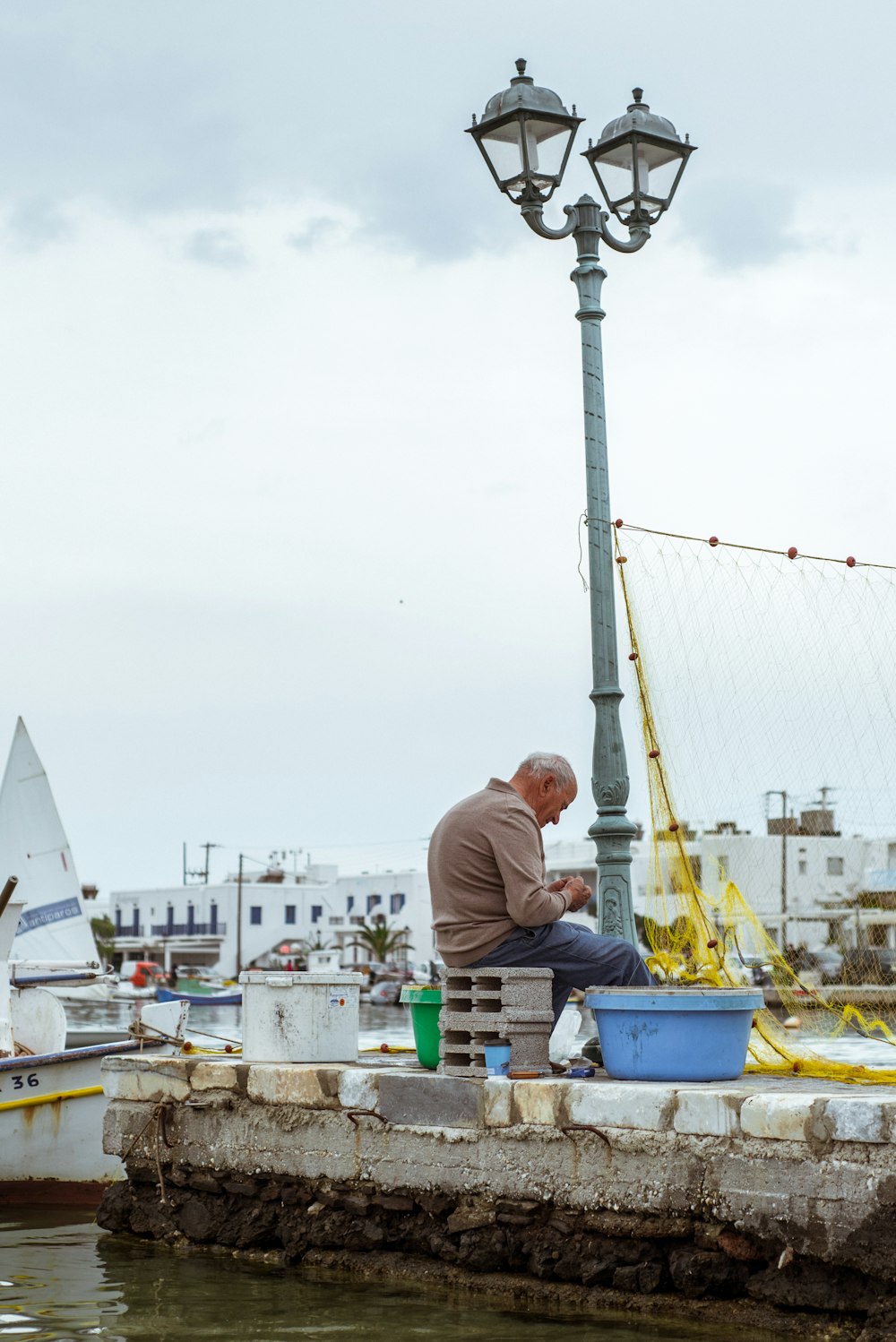 a man sitting on a dock next to a light pole