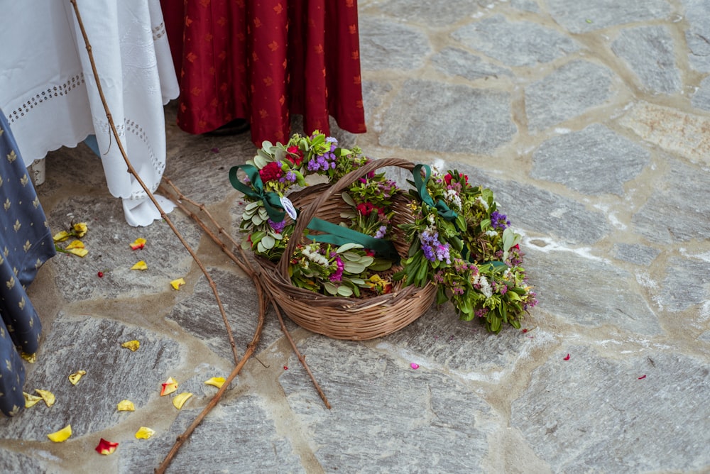 a basket filled with flowers sitting on top of a stone floor