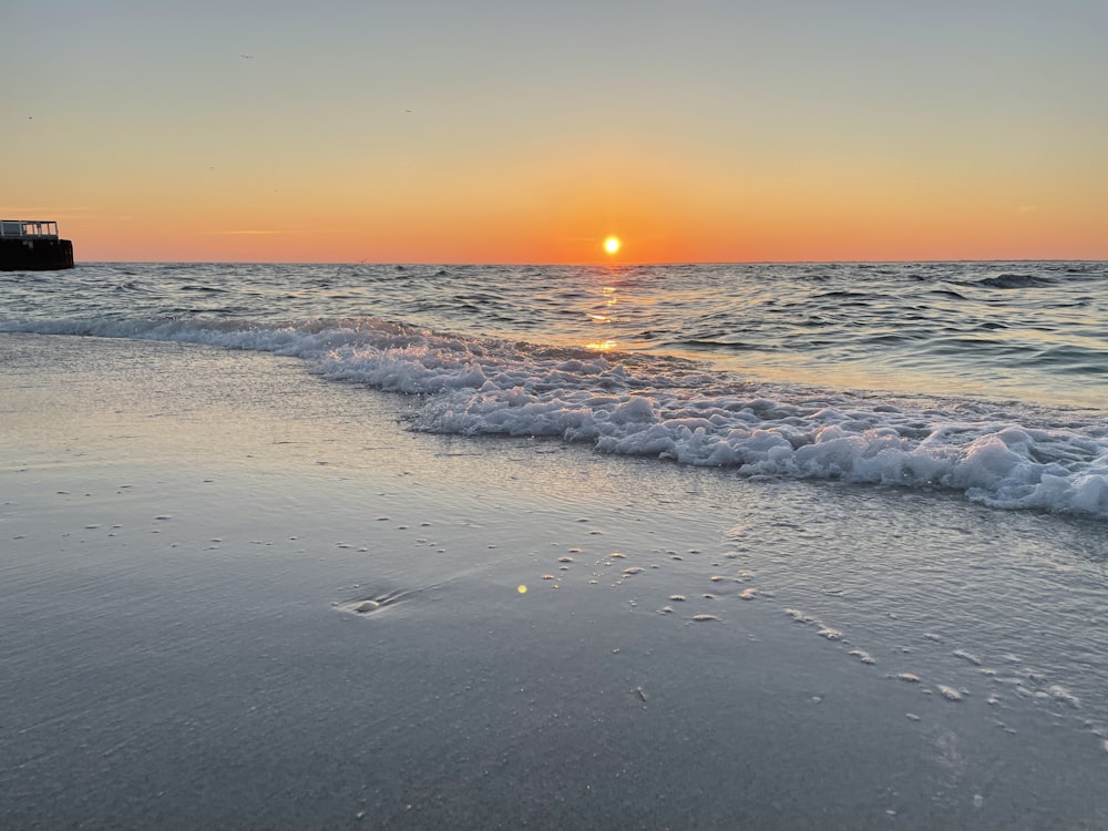 太陽がビーチの水面に沈んでいます