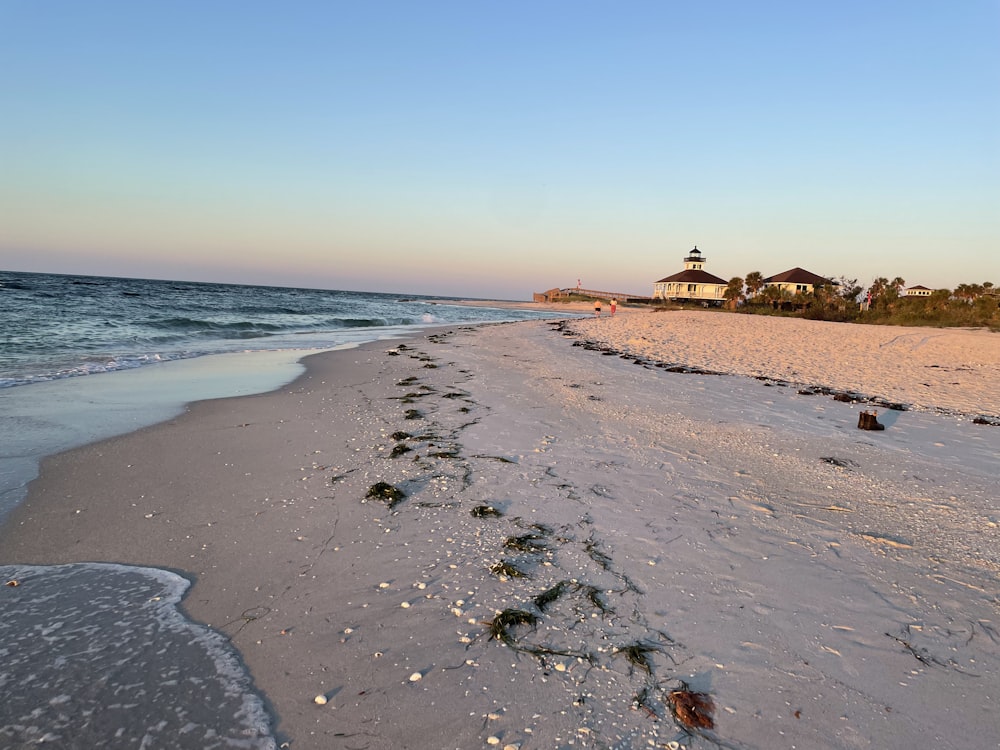 a sandy beach with a light house in the distance