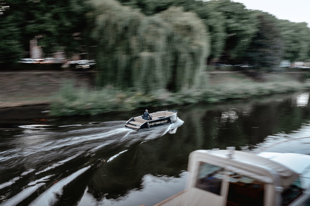 a boat traveling down a river next to a forest