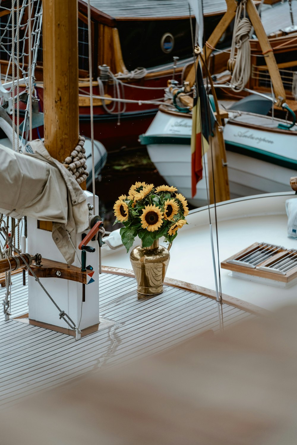 a vase of sunflowers sits on the deck of a sailboat