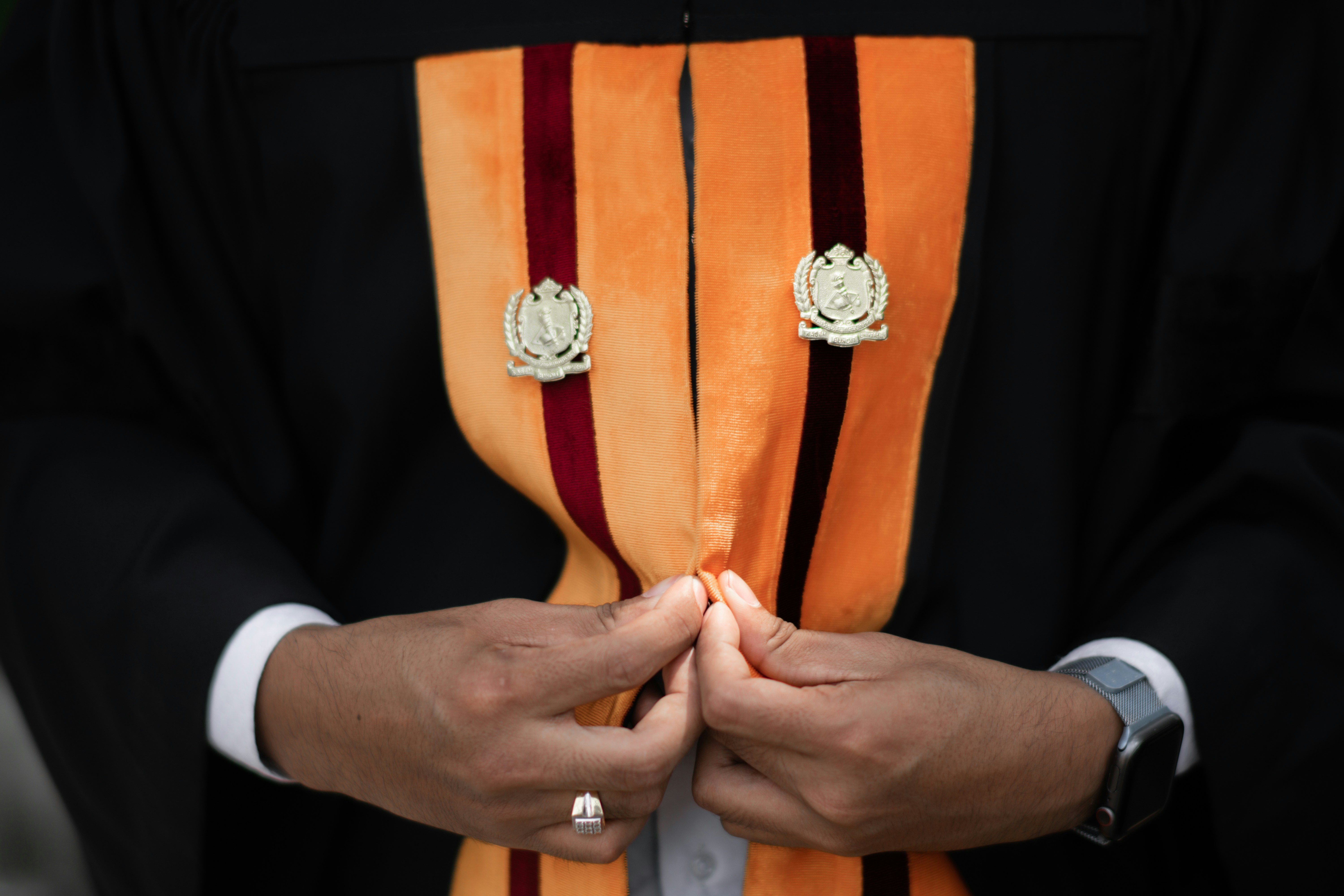 a man in a robe and tie holding his hands together