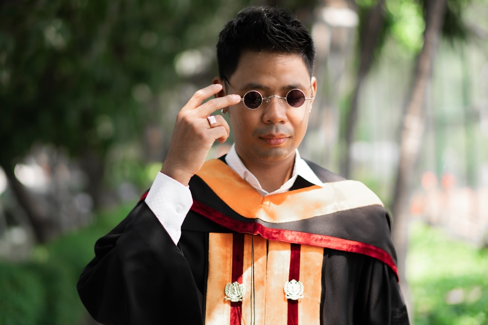 a man in a graduation gown holding a cell phone to his ear