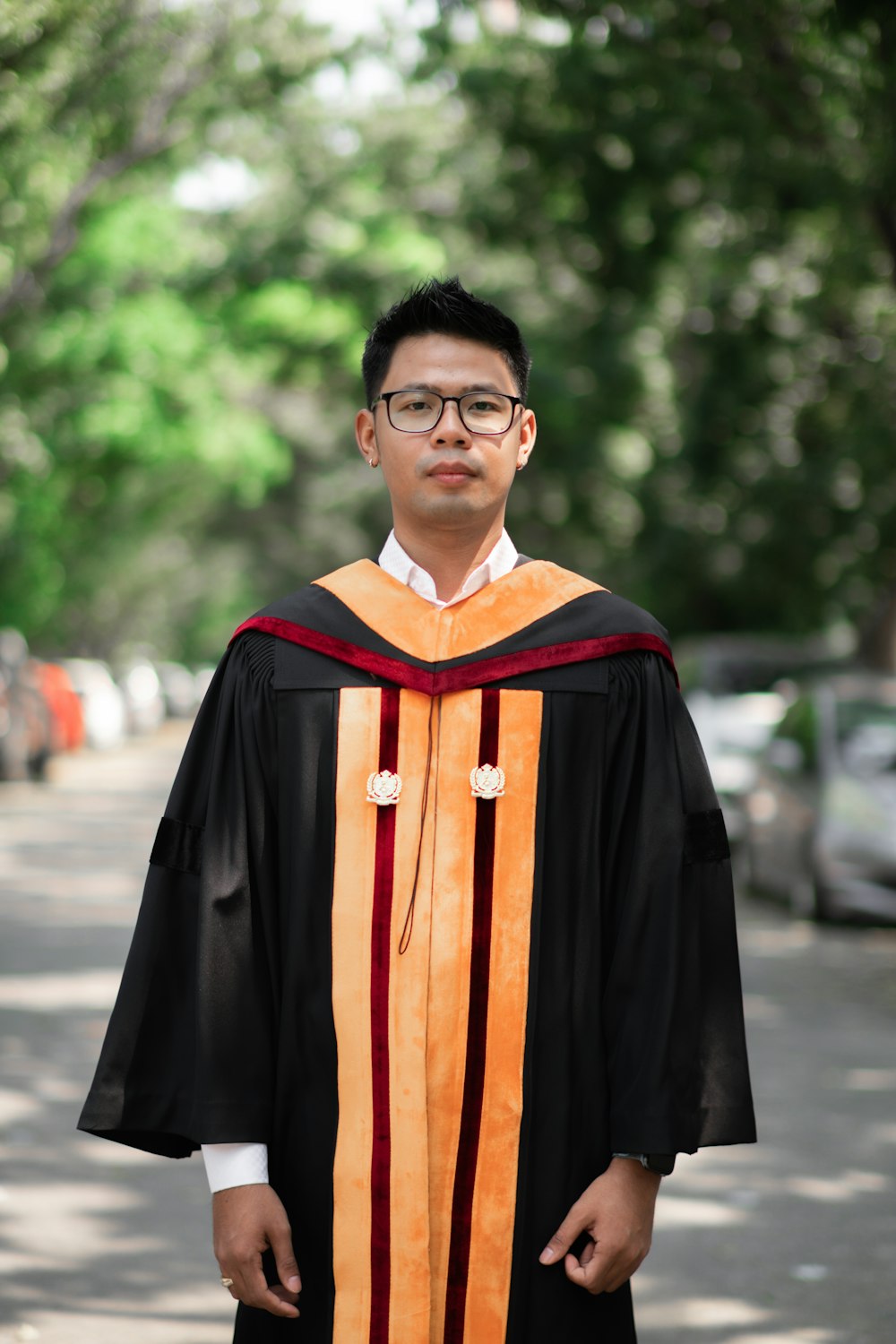 a man in a graduation gown standing on a street