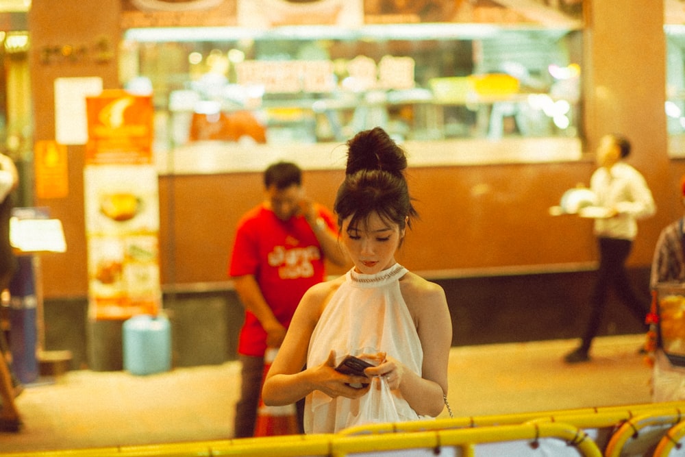 a woman in a white dress looking at her cell phone