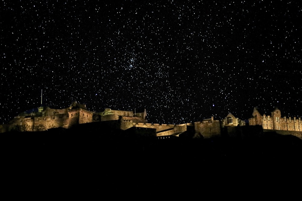 Um castelo iluminado à noite com estrelas no céu