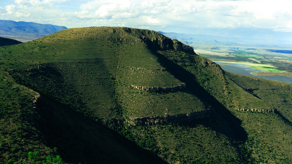 a view of a green mountain with a lake in the distance