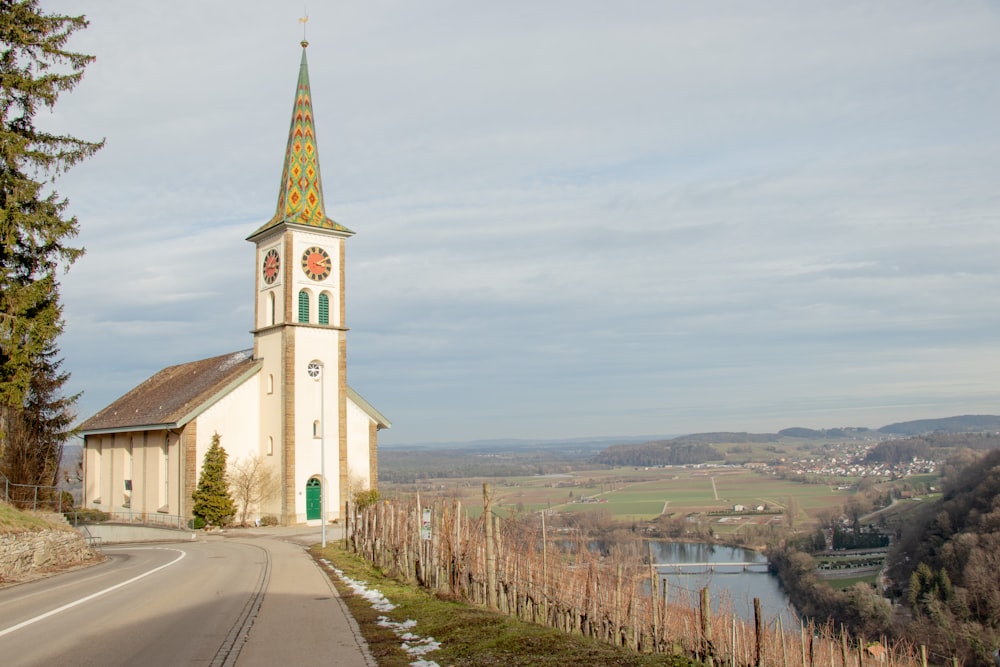 uma igreja com um campanário e um campanário à beira de uma estrada