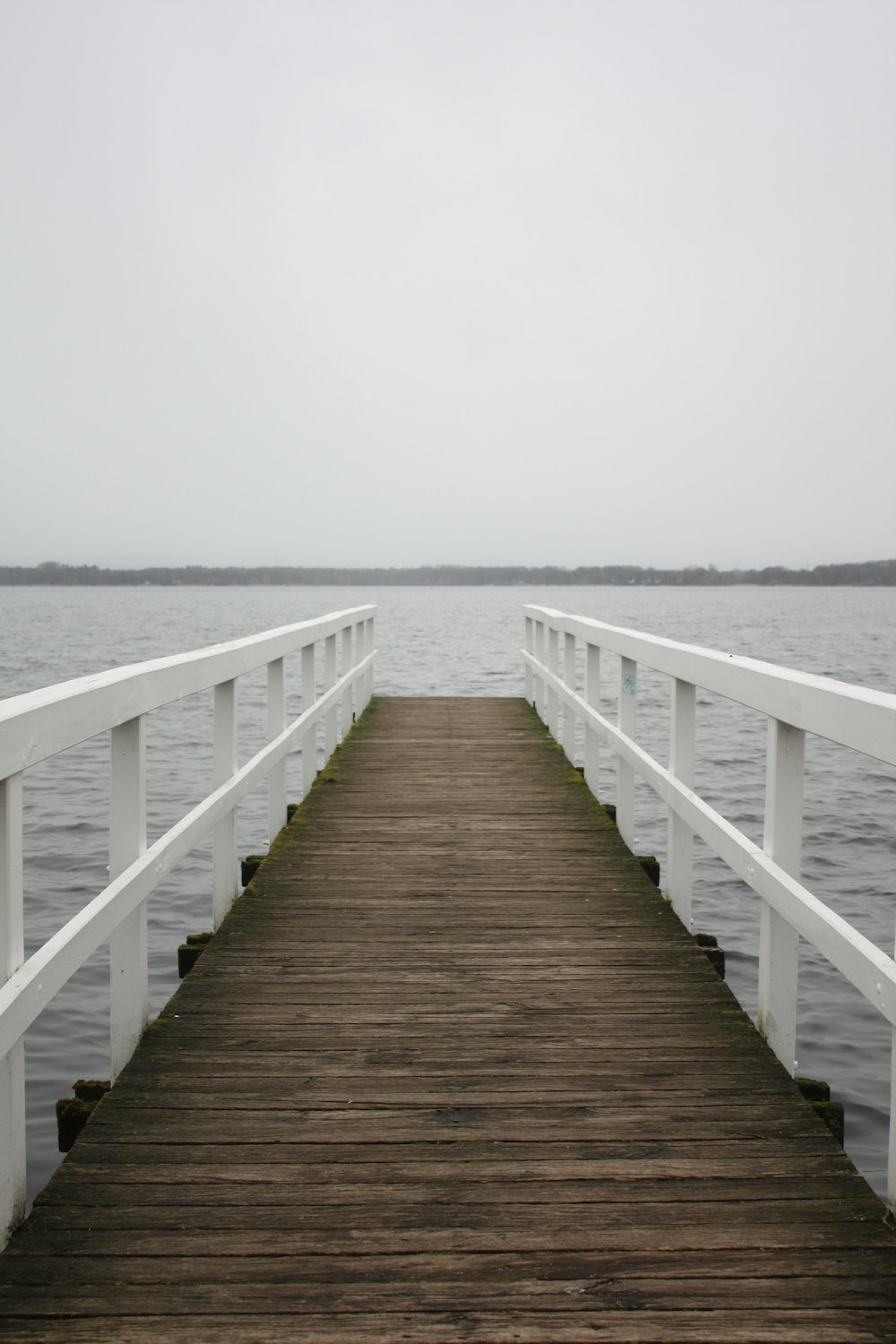 a white wooden pier with a body of water in the background
