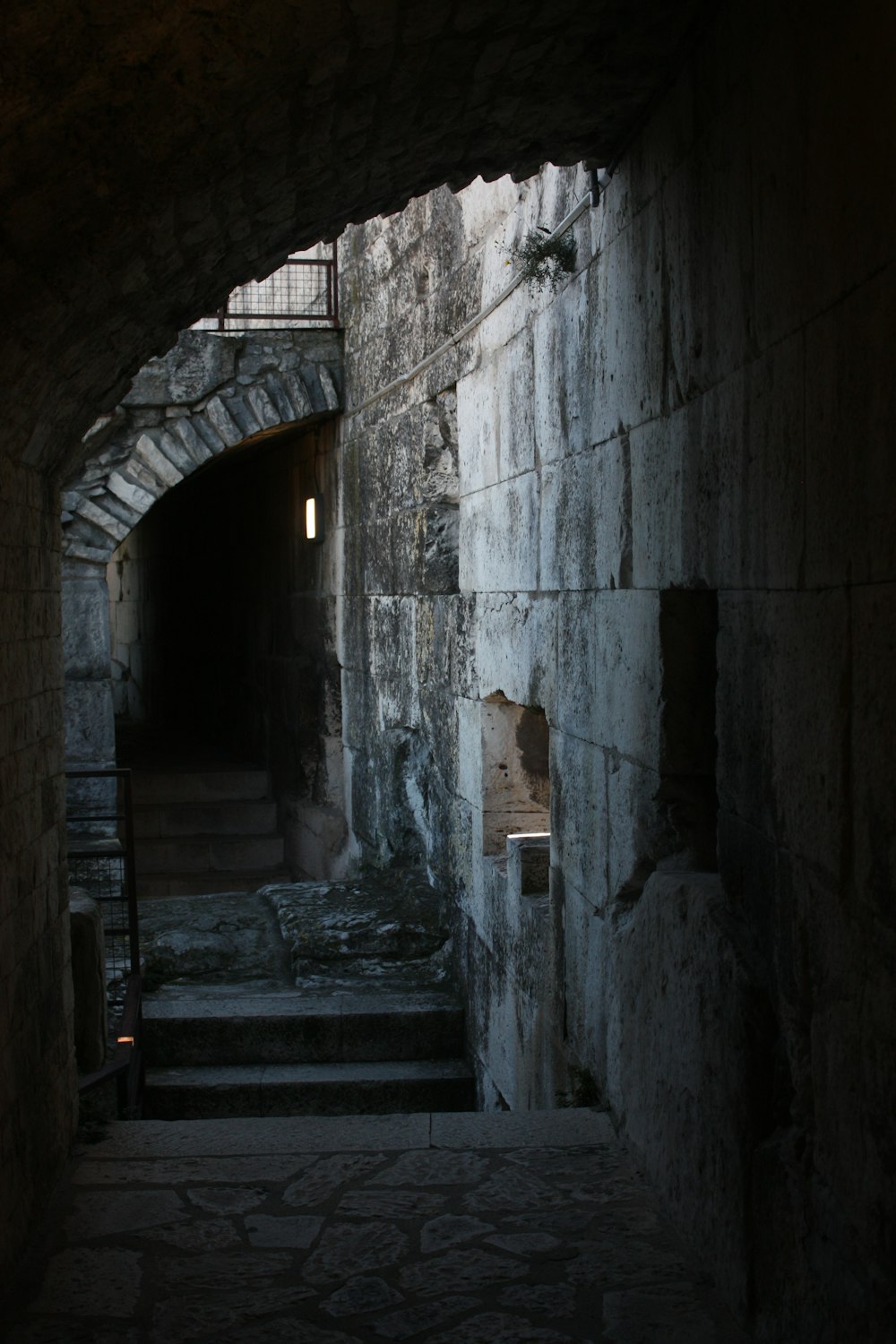 a dark alley with stairs leading to a light