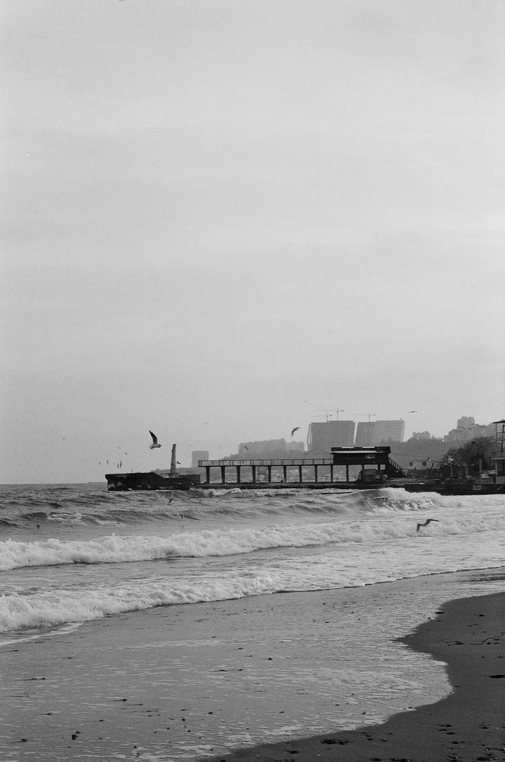 a black and white photo of a pier on the beach