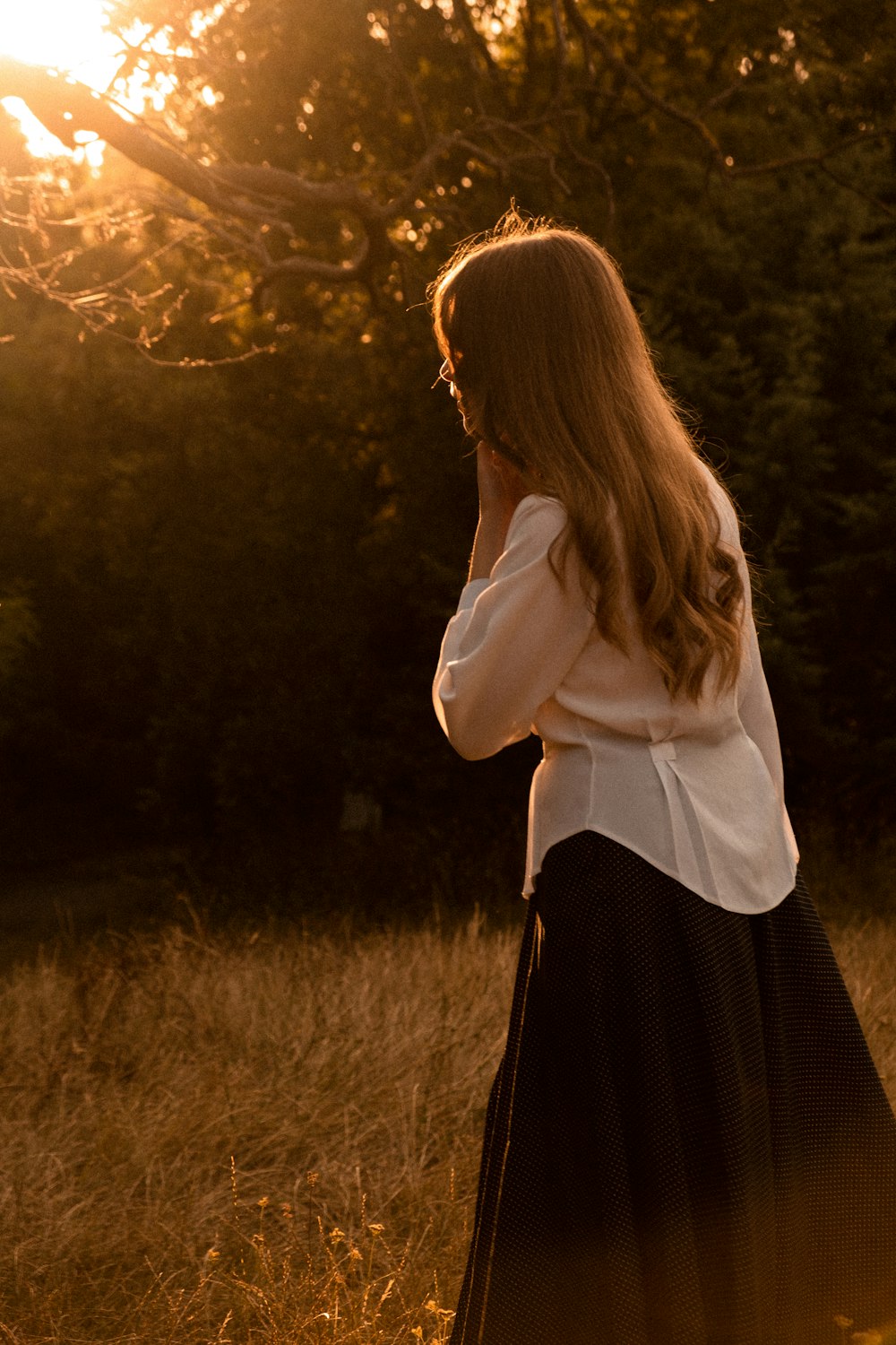 a woman standing in a field with trees in the background