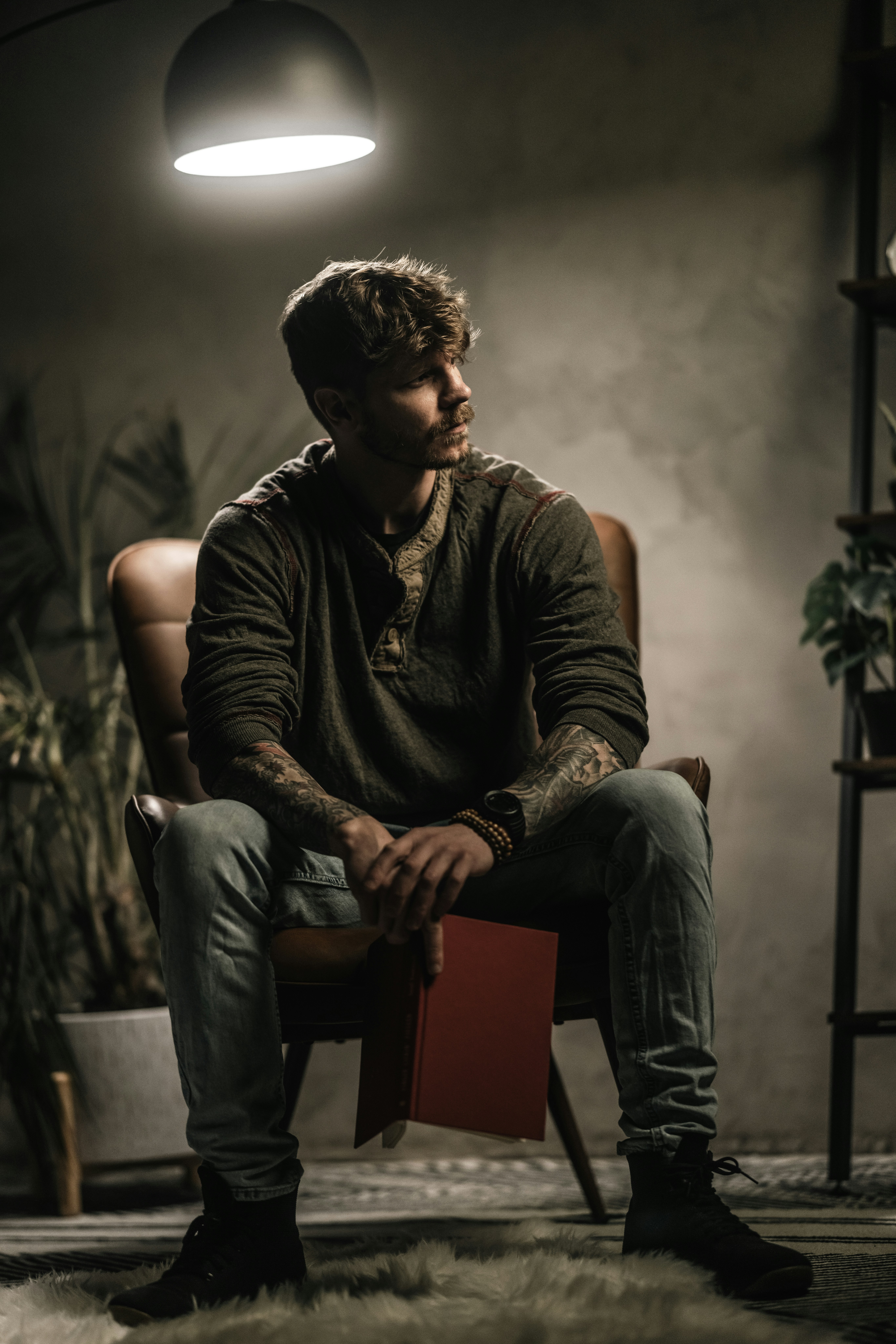 un homme assis sur une chaise avec un livre sur les genoux