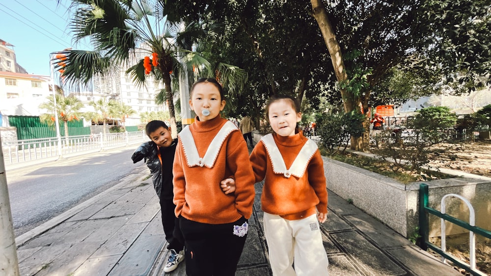 a couple of kids that are standing on a sidewalk