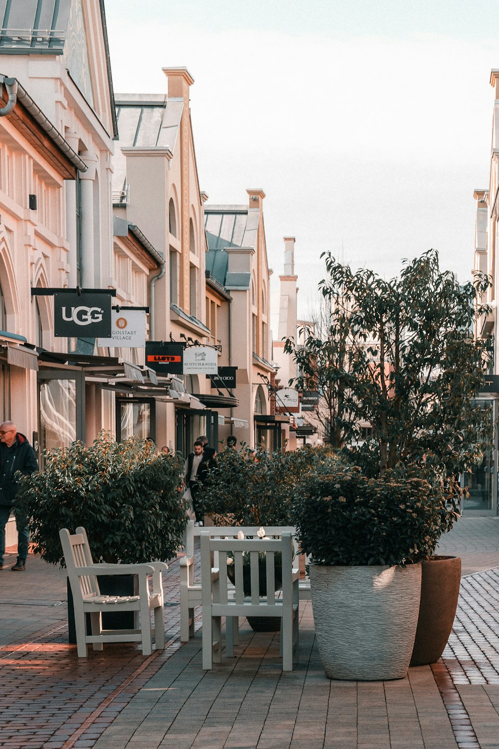 a couple of white chairs sitting on top of a sidewalk