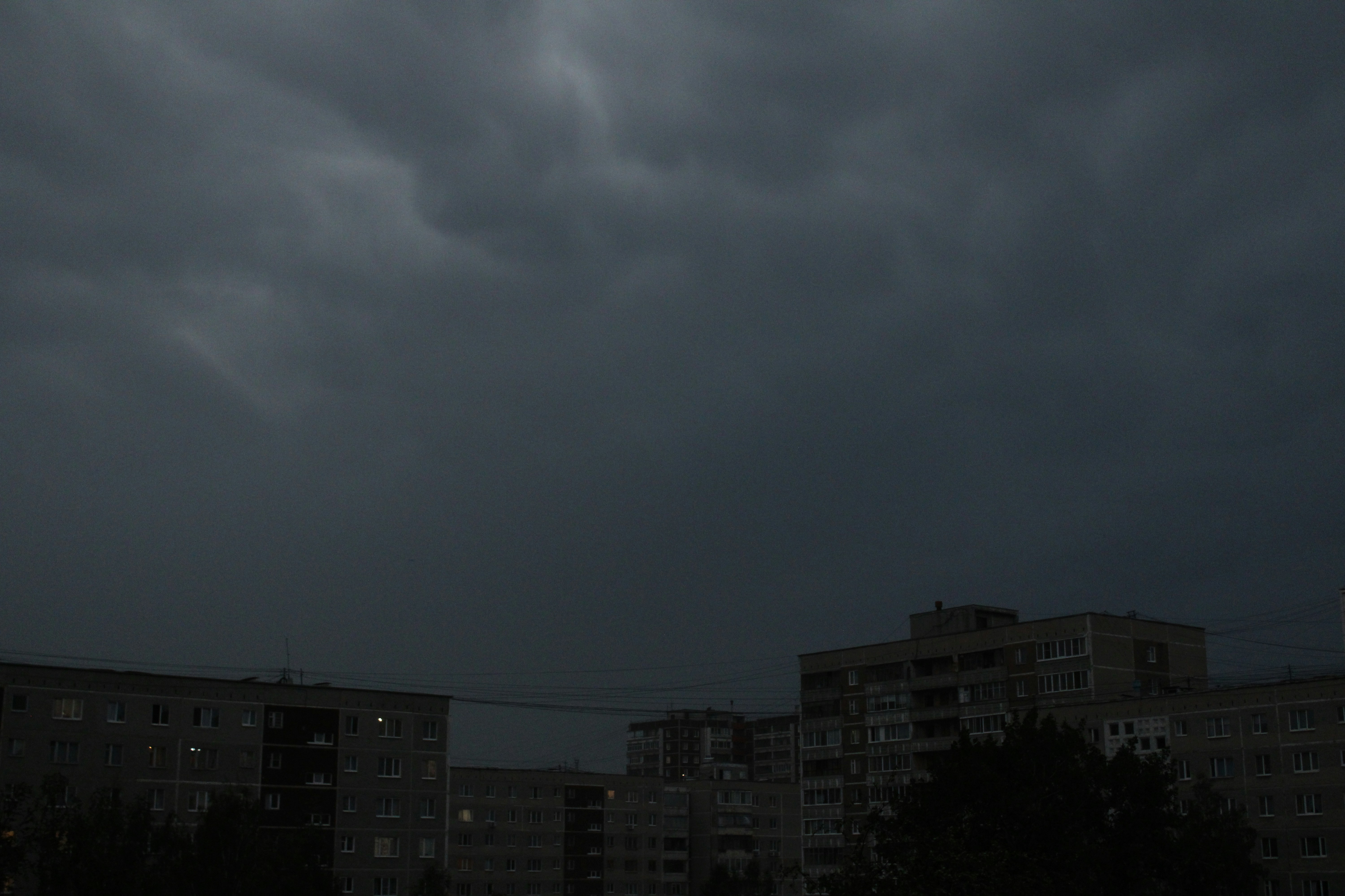 a dark sky with some buildings in the background