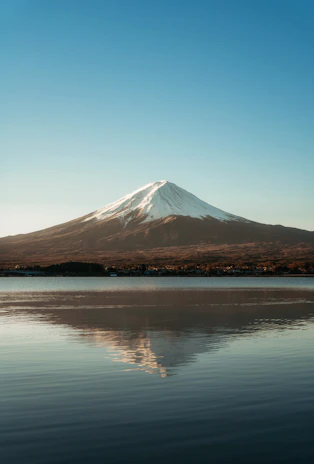 a mountain with a snow capped peak is reflected in the water
