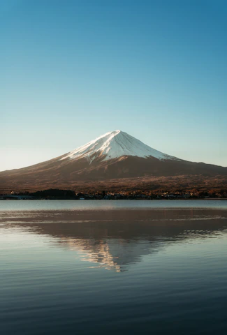 a mountain with a snow capped peak is reflected in the water
