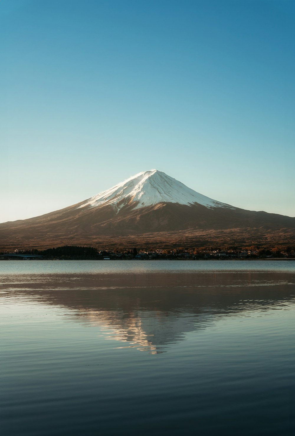 a mountain with a snow capped peak is reflected in the water