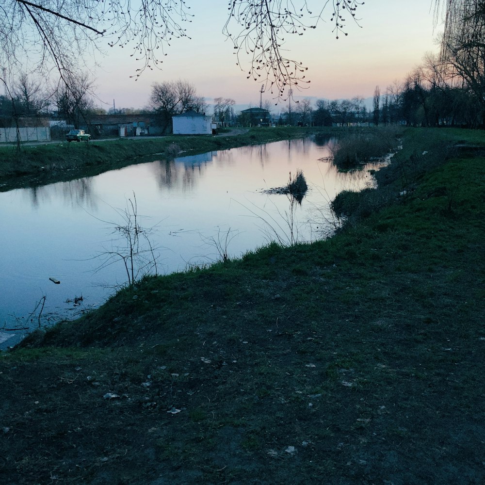 a body of water sitting next to a lush green field