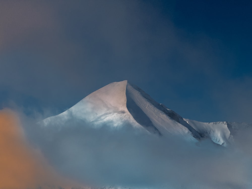 a mountain covered in snow under a cloudy sky