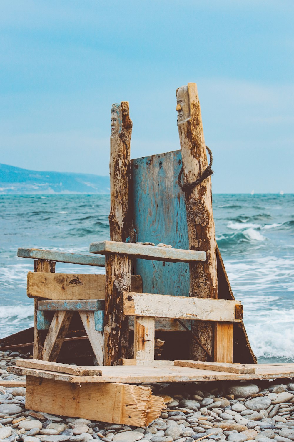 a wooden chair sitting on top of a beach next to the ocean