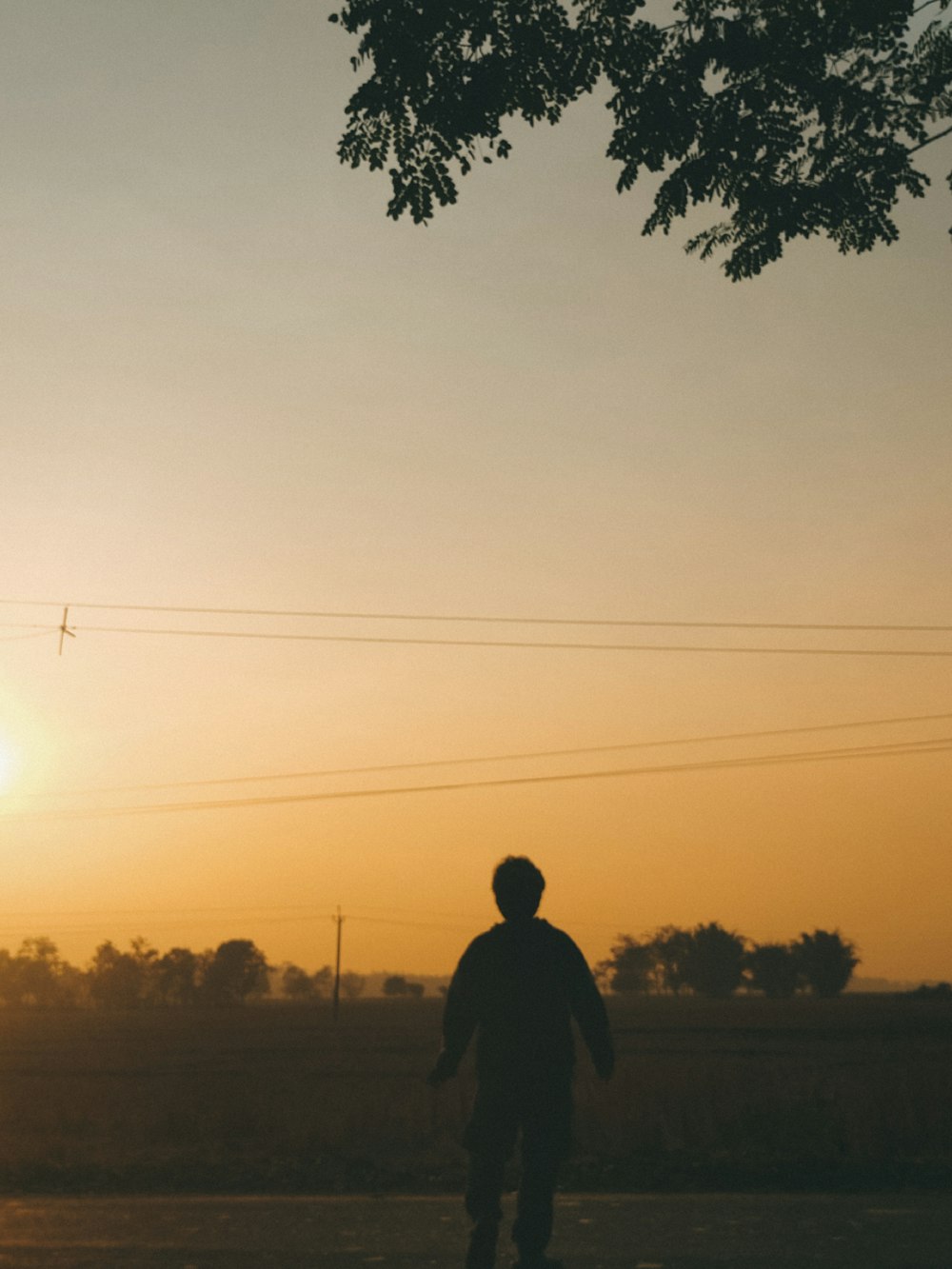 Ein Mann fährt bei Sonnenuntergang mit einem Skateboard eine Straße hinunter