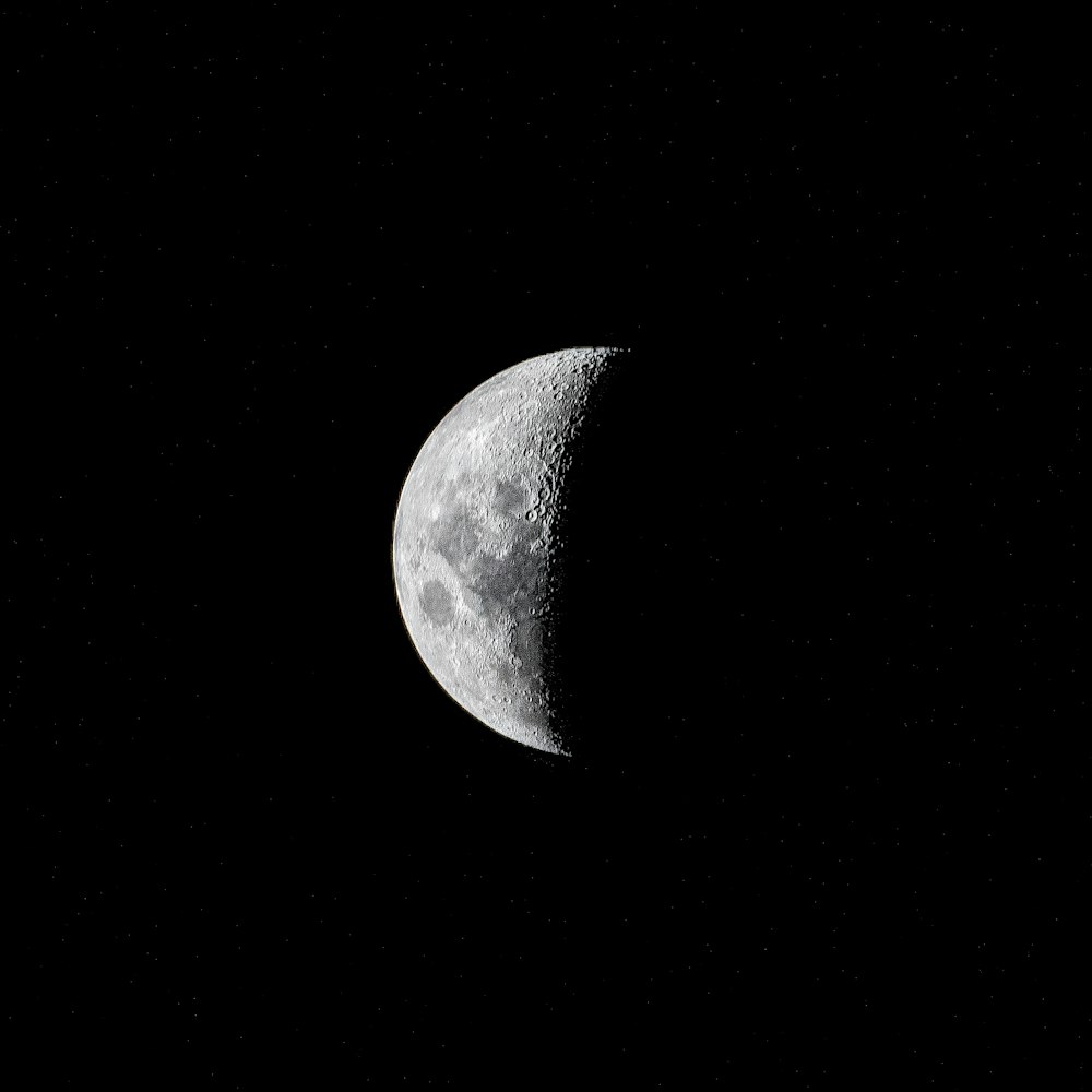 a half moon is seen in the dark sky