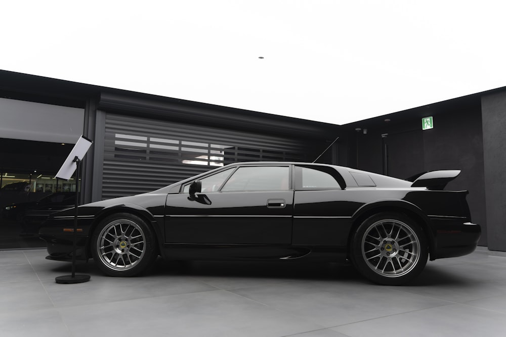 Une voiture de sport noire garée devant un garage