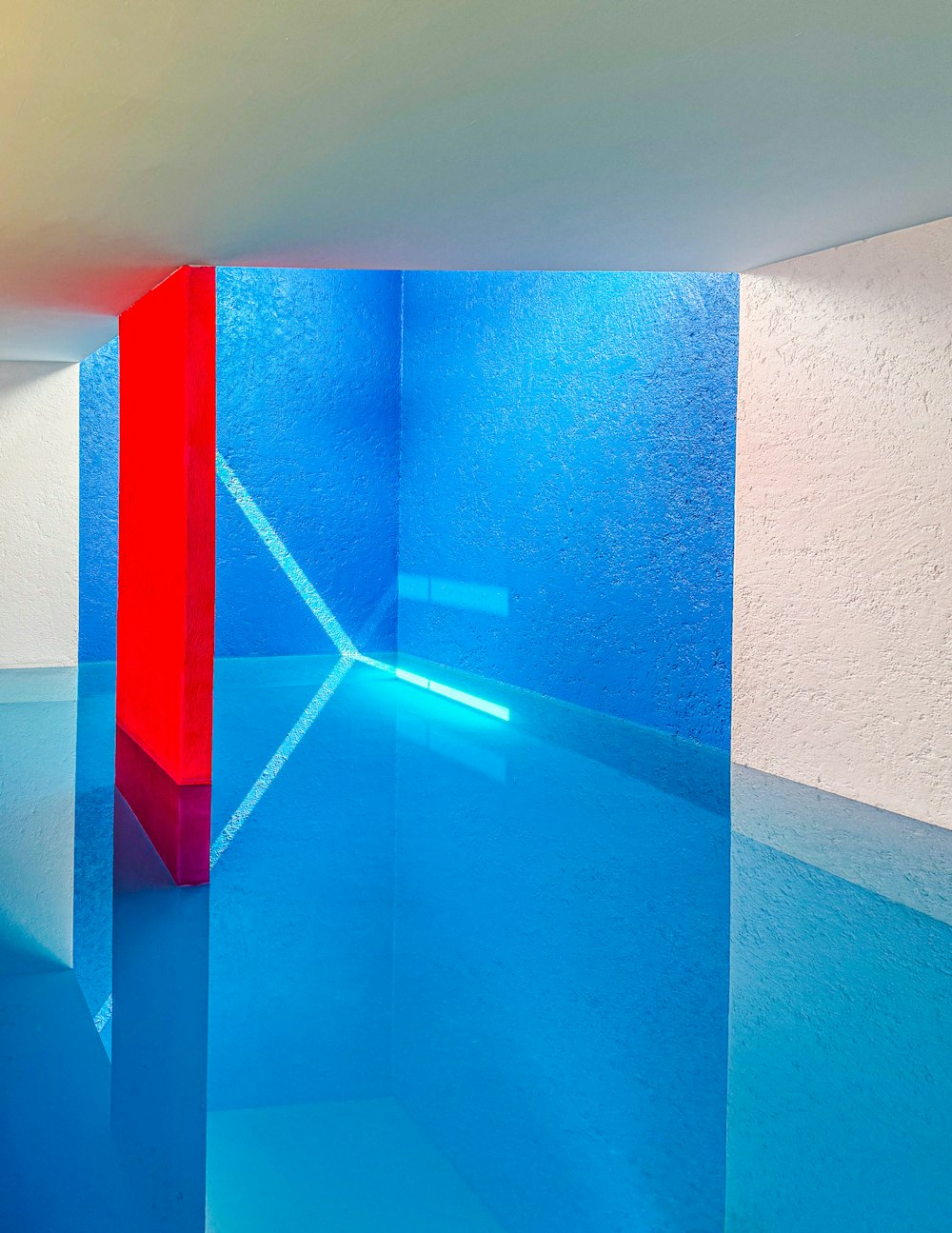 a room with a blue floor and a red column