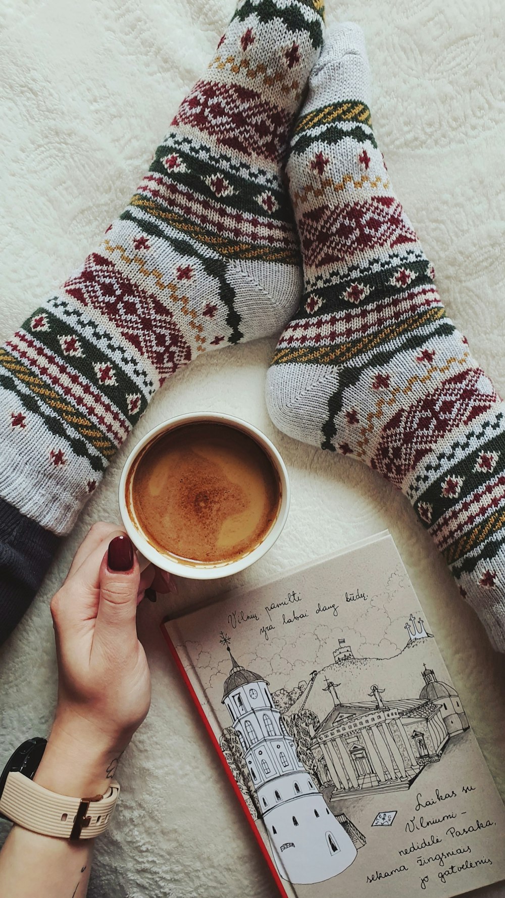 a person holding a cup of coffee next to a book