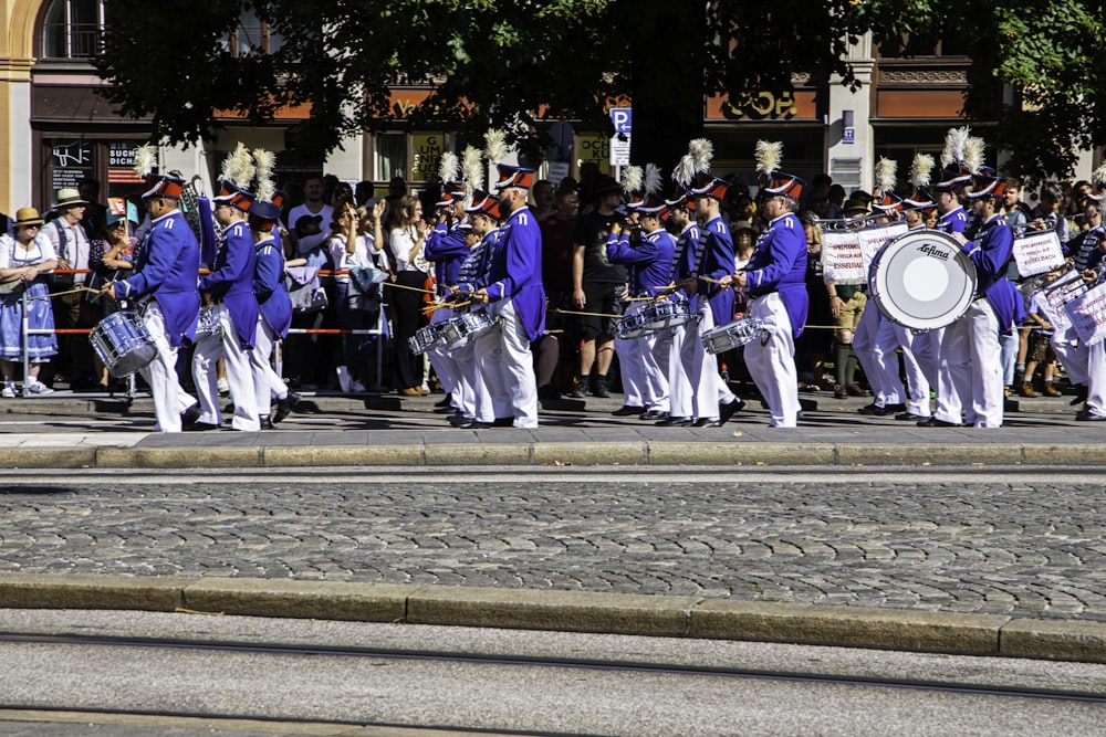 a group of men in blue and white uniforms marching down a street