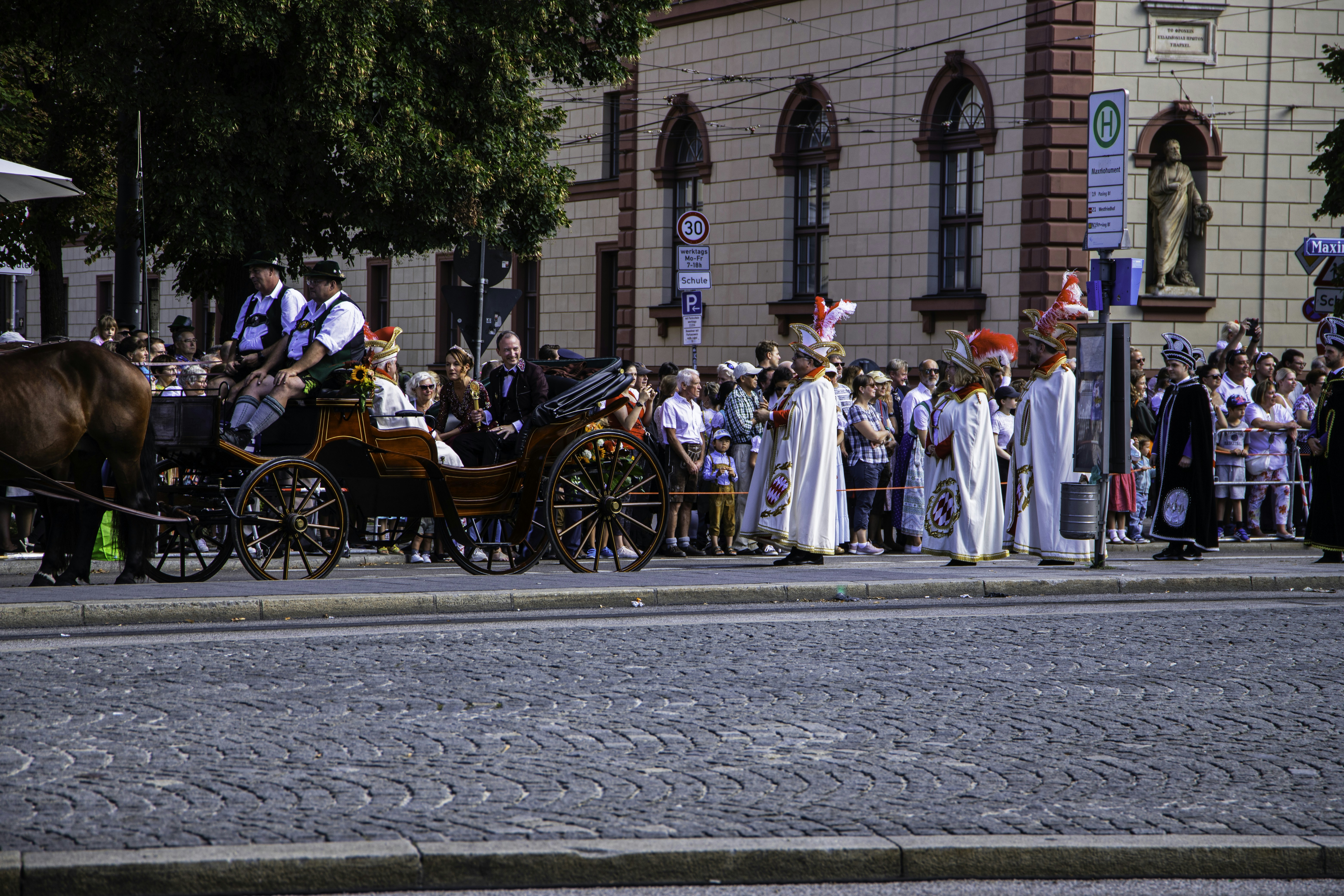 a horse drawn carriage driving down a street next to a crowd of people, 