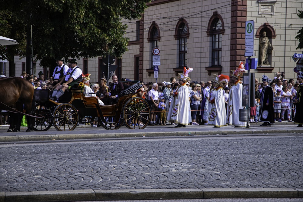 a horse drawn carriage driving down a street next to a crowd of people