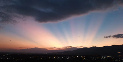the sun is setting over a city with mountains in the background