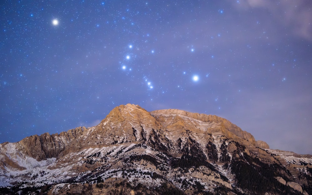 a mountain covered in snow under a sky filled with stars