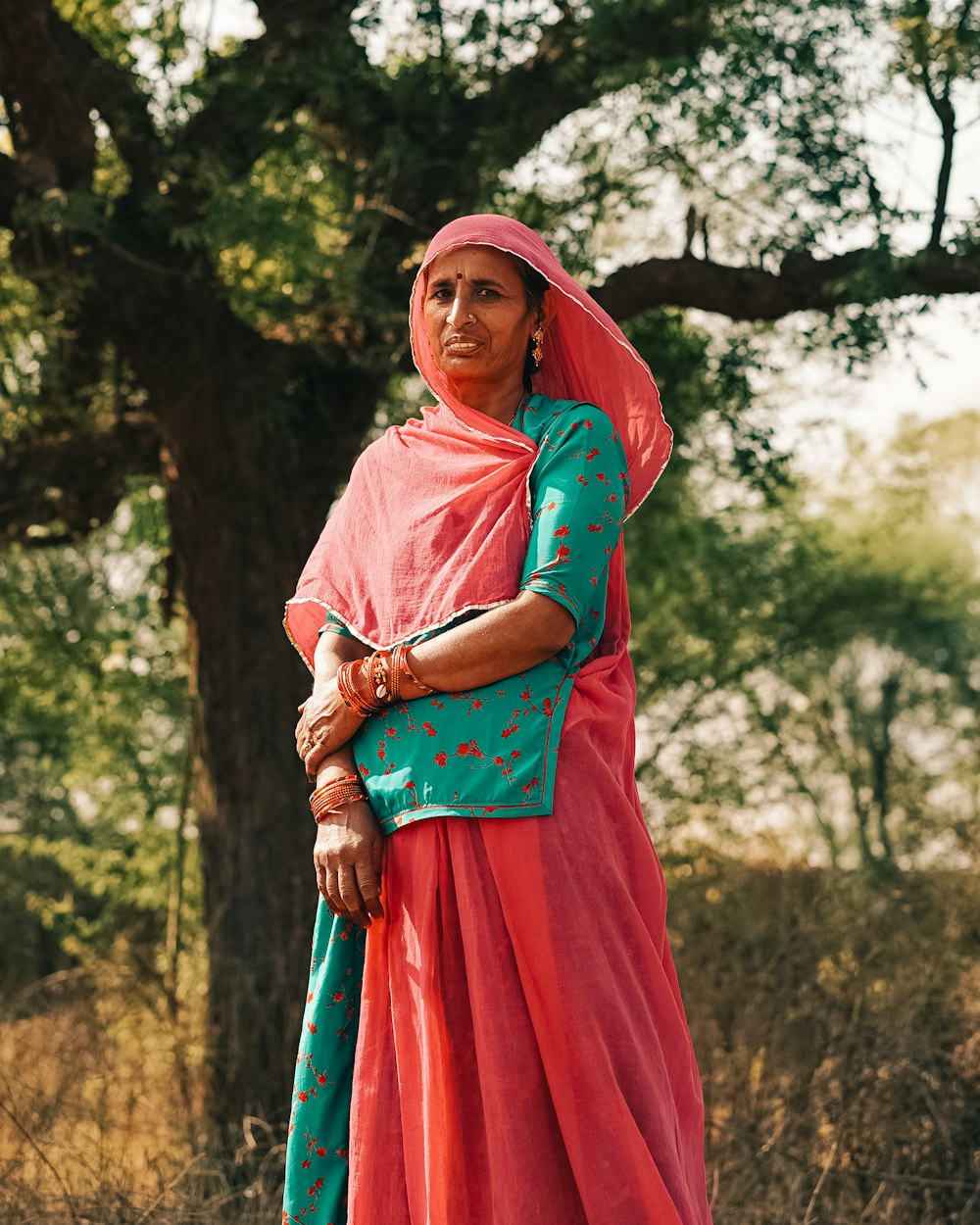 a woman in a pink and green dress standing in a field