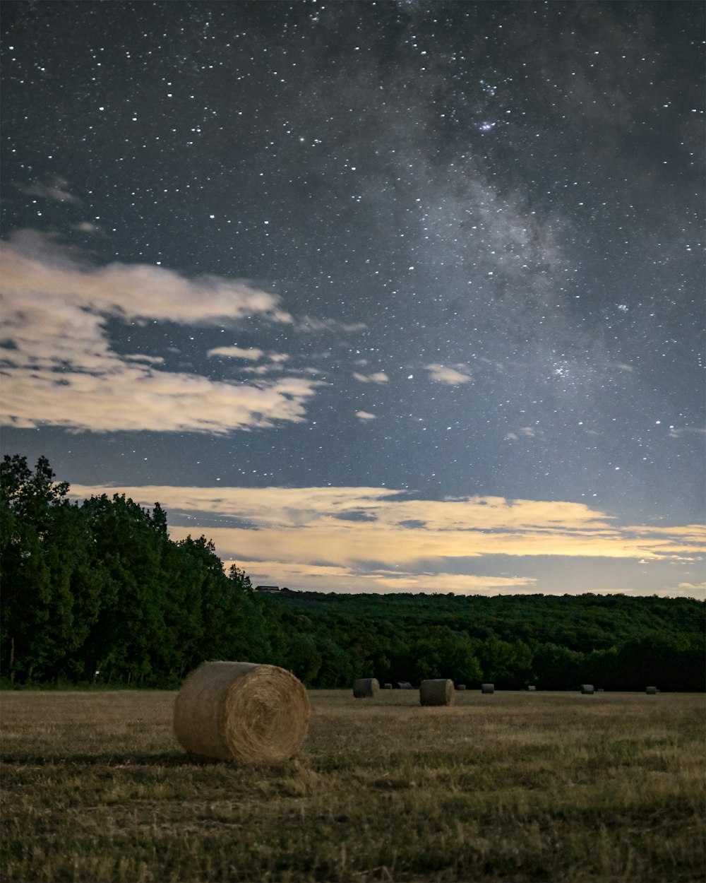 a field with hay bales under a night sky