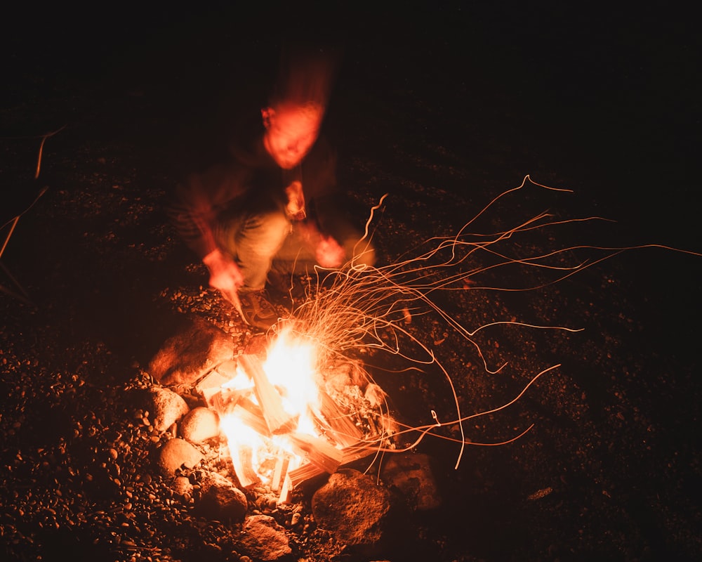 a person standing over a fire in the dark