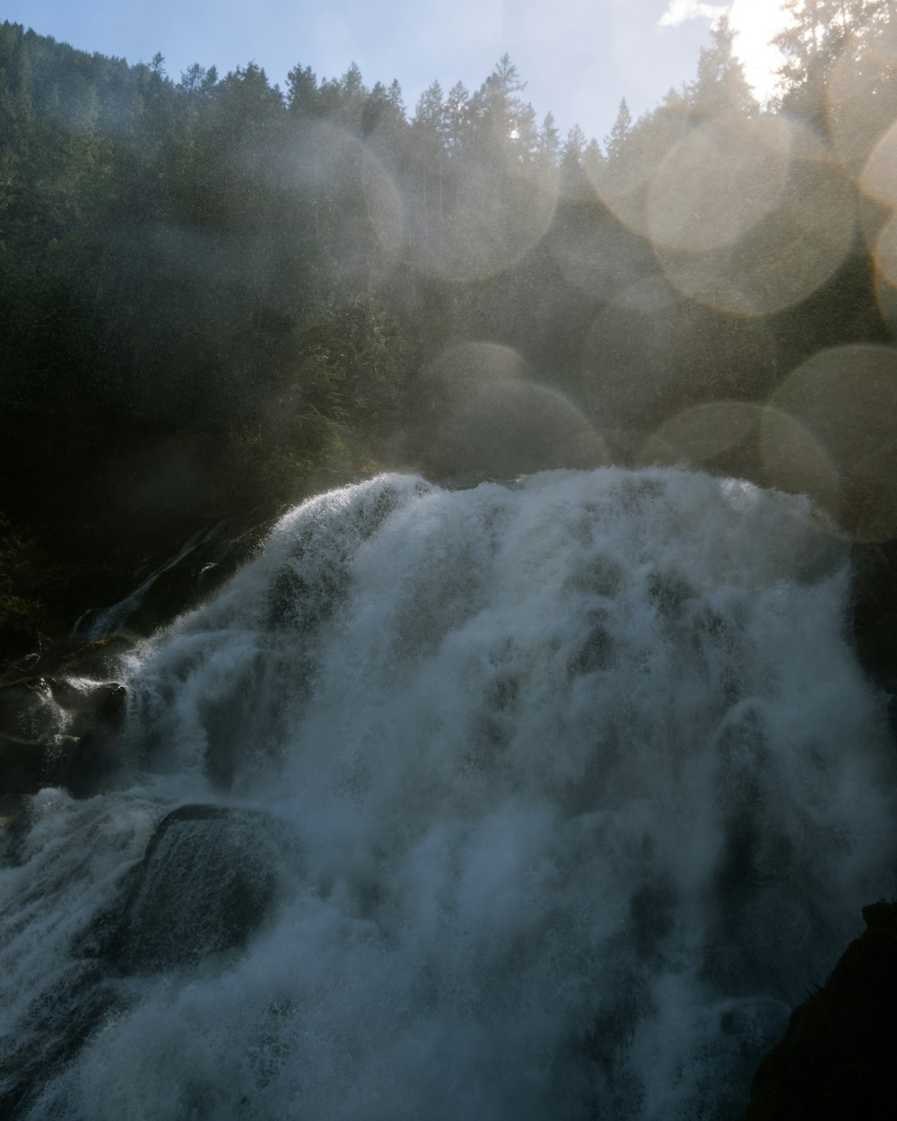 the sun shines on a waterfall in the woods