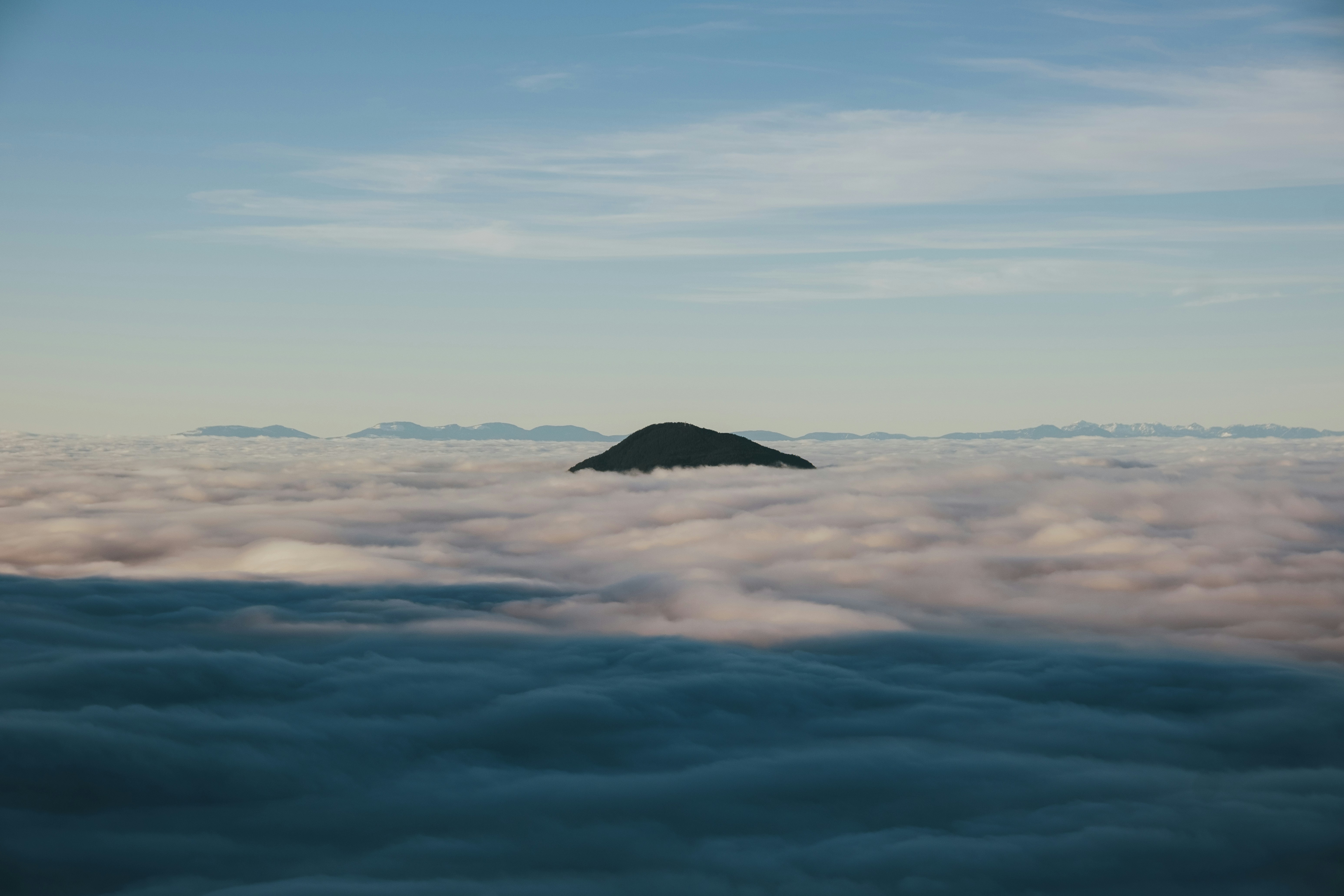 a mountain in the middle of a sea of clouds, 